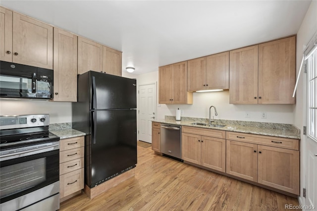 kitchen with light stone counters, light hardwood / wood-style floors, sink, and black appliances