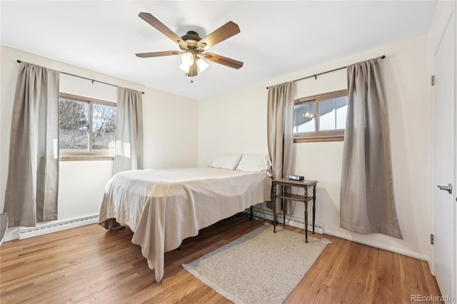 bedroom featuring ceiling fan, a baseboard radiator, and light hardwood / wood-style floors