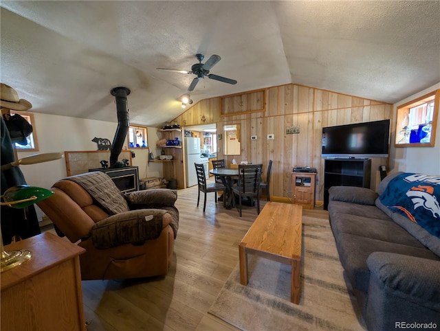 2117 Badger Creek Rd, Hartsel, CO 80449 - living room with a wood stove, lofted ceiling, a textured ceiling, light wood finished floors, and a ceiling fan