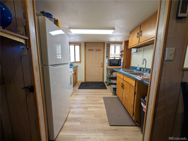 2117 Badger Creek Rd, Hartsel, CO 80449 - kitchen with freestanding refrigerator, black microwave, light wood finished floors, dark countertops, and brown cabinets