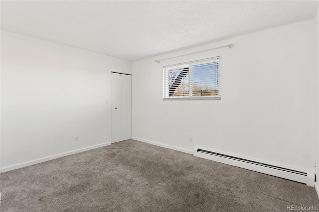 carpeted spare room featuring a baseboard heating unit, a textured ceiling, and baseboards