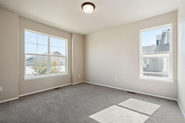 carpeted empty room featuring baseboards