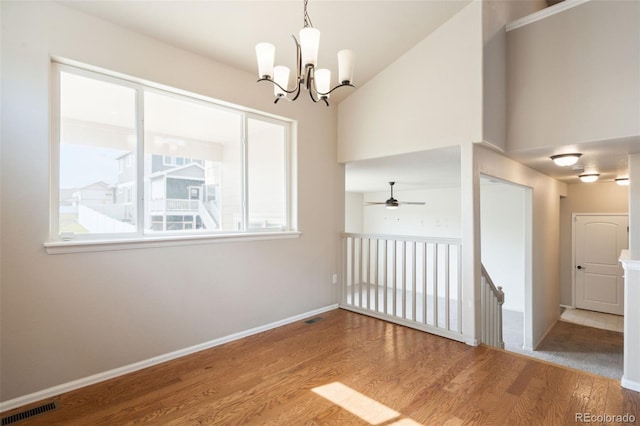 spare room with wood finished floors, a chandelier, and ceiling fan