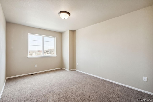 carpeted empty room featuring baseboards