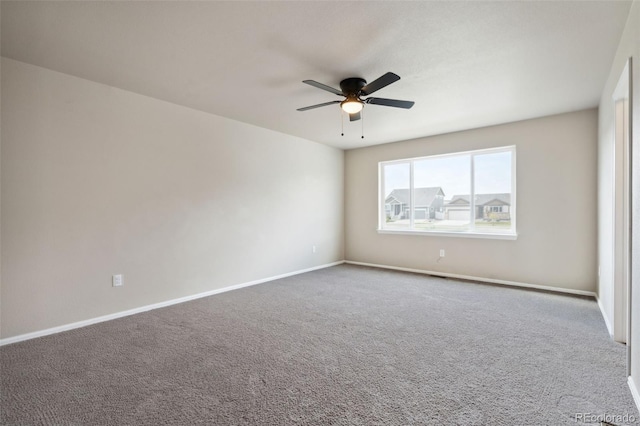 carpeted empty room featuring ceiling fan and baseboards