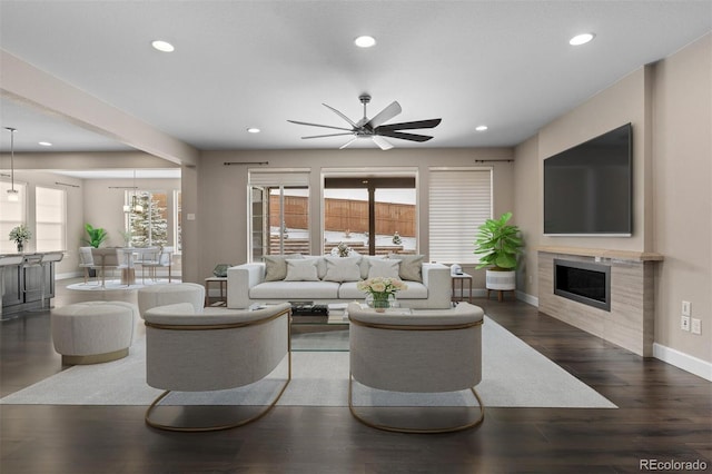 living room with ceiling fan with notable chandelier and dark hardwood / wood-style floors