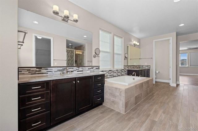 bathroom featuring decorative backsplash, vanity, ceiling fan, hardwood / wood-style floors, and shower with separate bathtub