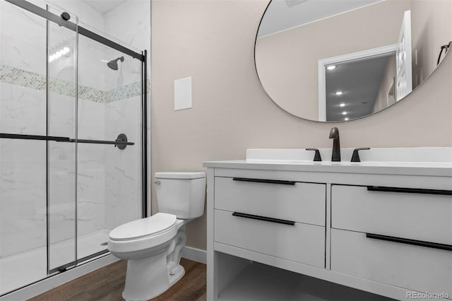 bathroom with hardwood / wood-style floors, vanity, toilet, and walk in shower