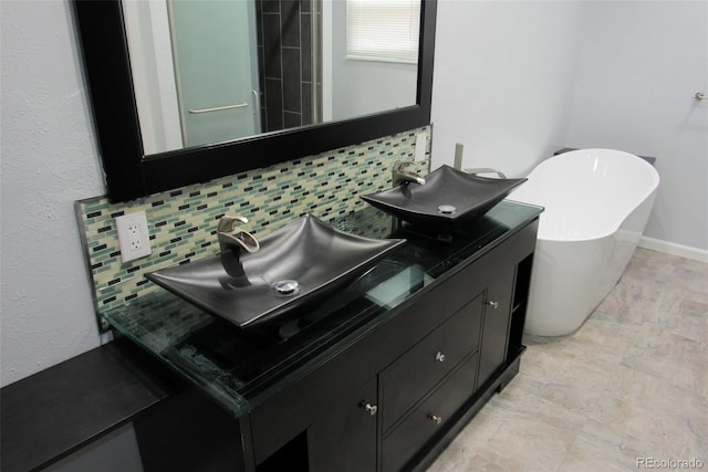 bathroom featuring tasteful backsplash, a freestanding bath, and double vanity