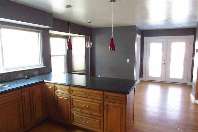 12381 E Vassar Dr, Aurora, CO 80014 - kitchen with a peninsula, wood finished floors, brown cabinetry, french doors, and decorative light fixtures