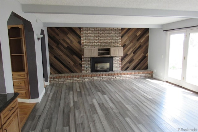 12381 E Vassar Dr, Aurora, CO 80014 - unfurnished living room featuring wood finished floors, beam ceiling, wooden walls, a fireplace, and baseboards