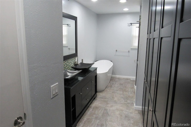 12381 E Vassar Dr, Aurora, CO 80014 - bathroom with a soaking tub, vanity, and baseboards