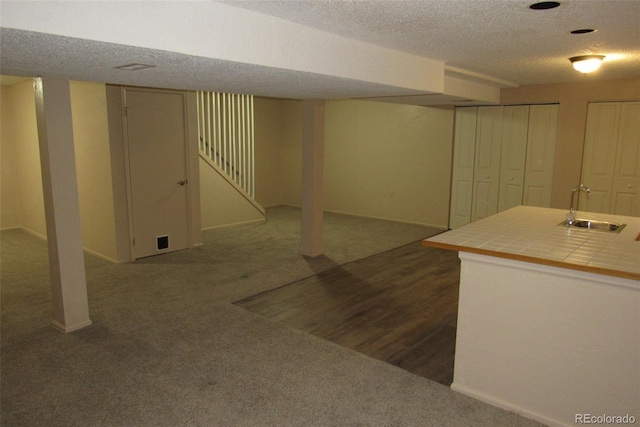 12381 E Vassar Dr, Aurora, CO 80014 - finished basement featuring a sink, dark colored carpet, a textured ceiling, and baseboards