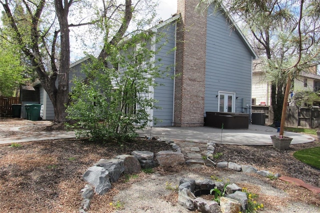 12381 E Vassar Dr, Aurora, CO 80014 - view of home's exterior featuring a jacuzzi, fence, french doors, a patio area, and a chimney