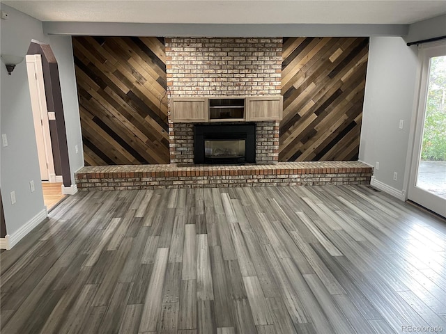 12381 E Vassar Dr, Aurora, CO 80014 - unfurnished living room featuring wood finished floors, wooden walls, baseboards, and a brick fireplace