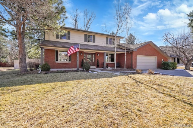 traditional-style house with brick siding, covered porch, an attached garage, a front yard, and driveway