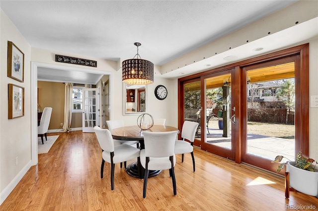 dining space with french doors, light wood-style flooring, and baseboards