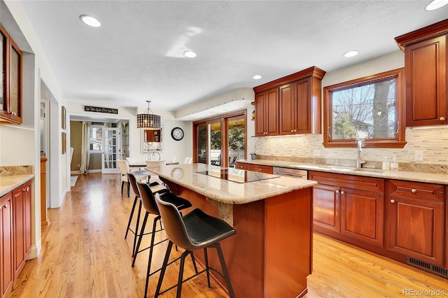 kitchen with a breakfast bar area, a kitchen island, a sink, and light wood-style floors