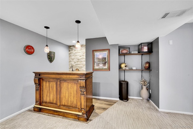 bar with baseboards, wet bar, visible vents, and pendant lighting