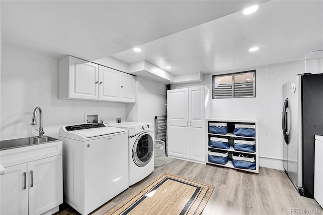 laundry room featuring light wood finished floors, recessed lighting, cabinet space, a sink, and separate washer and dryer