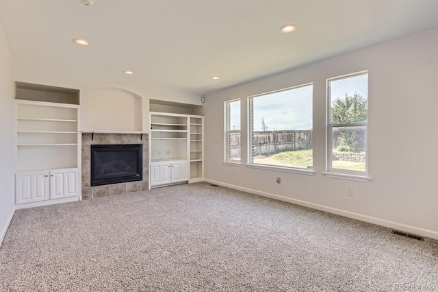 19033 E 22nd Cir, Aurora, CO 80011 - unfurnished living room with carpet floors, recessed lighting, a tiled fireplace, and built in shelves