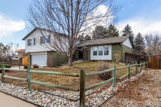 split level home with a fenced front yard, brick siding, and an attached garage