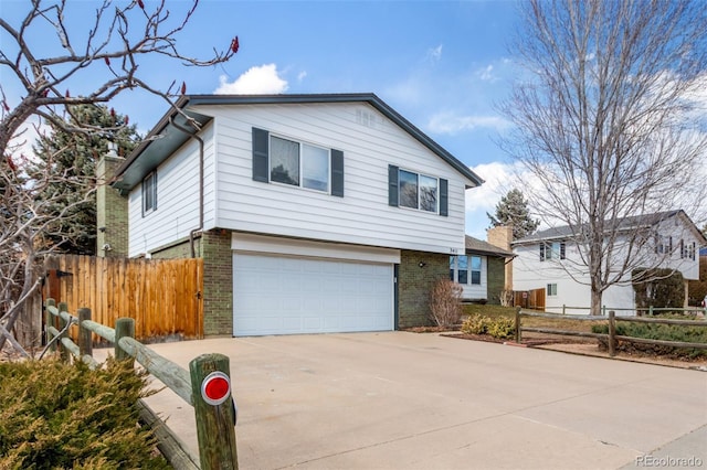 view of front of house with concrete driveway, brick siding, an attached garage, and fence