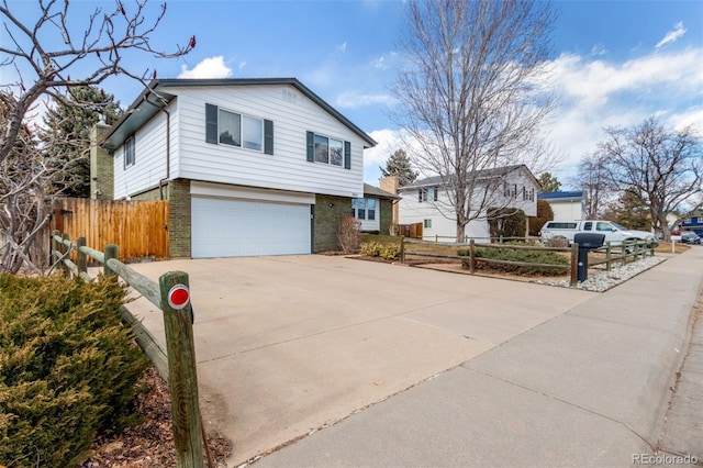 view of front facade with driveway, an attached garage, fence, and brick siding