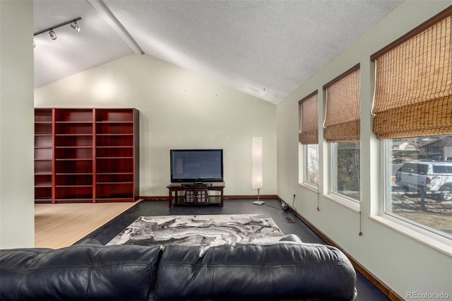 living area with lofted ceiling with beams, a textured ceiling, and baseboards