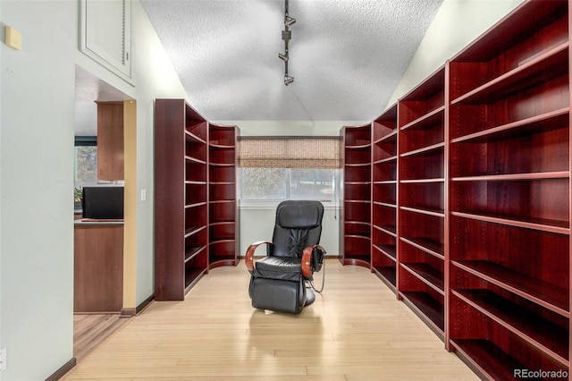 sitting room featuring a textured ceiling, light wood-type flooring, and baseboards