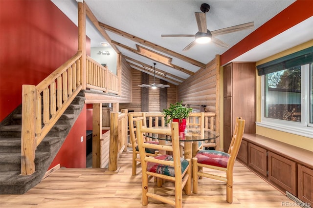 dining area with lofted ceiling with beams, light wood-type flooring, stairs, and rustic walls