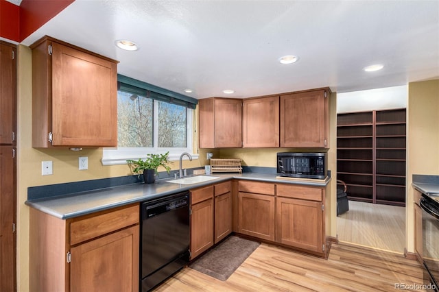 kitchen with brown cabinetry, a sink, and black appliances