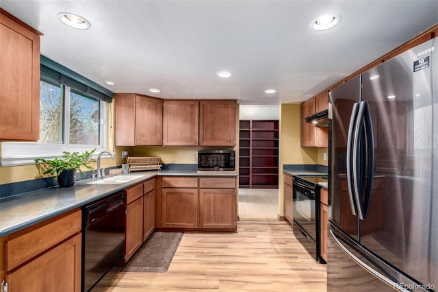 kitchen with recessed lighting, a sink, light wood-style floors, brown cabinets, and black appliances