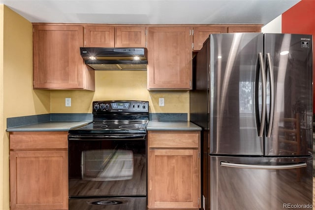 kitchen with brown cabinets, freestanding refrigerator, black range with electric cooktop, and under cabinet range hood