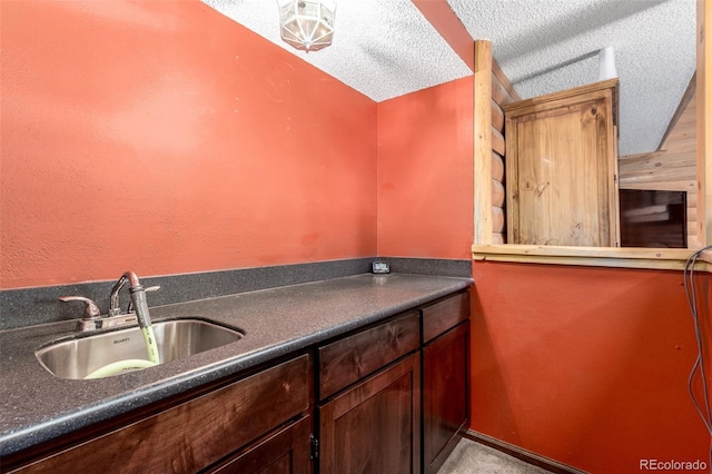 kitchen with dark countertops, a textured ceiling, and a sink