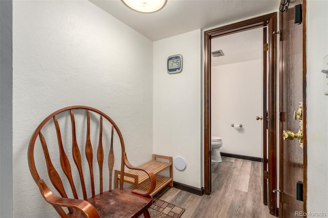 sitting room with light wood-type flooring, baseboards, and visible vents