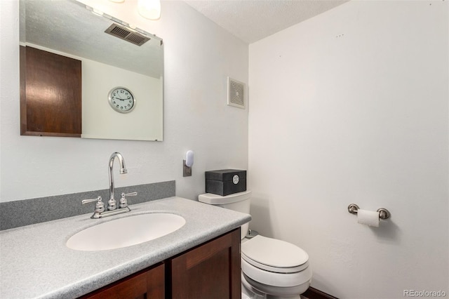 half bathroom with toilet, visible vents, a textured ceiling, and vanity