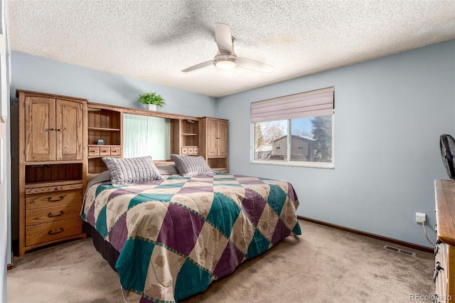 bedroom featuring ceiling fan, a textured ceiling, light colored carpet, visible vents, and baseboards