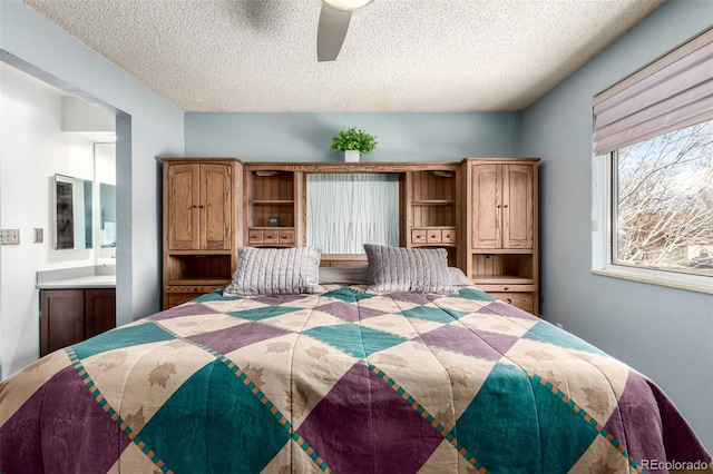 bedroom with ceiling fan, a textured ceiling, and ensuite bath