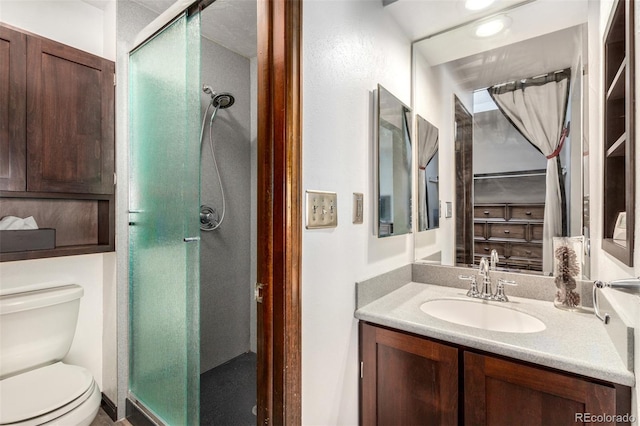 bathroom featuring toilet, a stall shower, and vanity