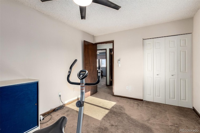 exercise area featuring light colored carpet, a textured ceiling, and baseboards