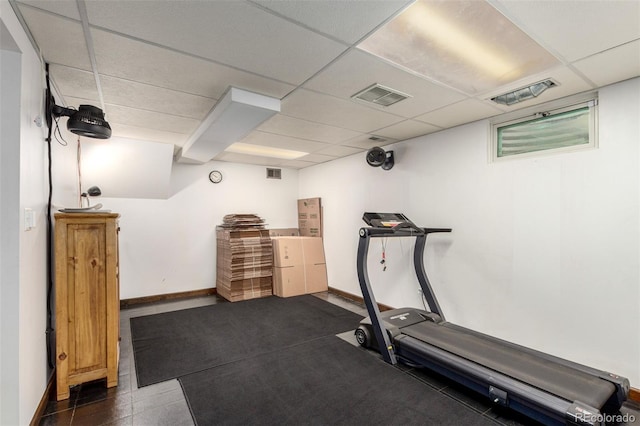 exercise area featuring a paneled ceiling, visible vents, and baseboards