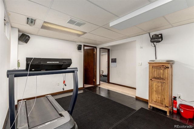 workout area with a paneled ceiling, visible vents, and baseboards