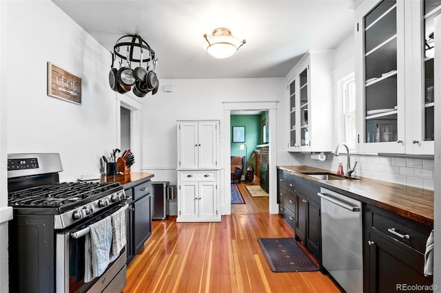 4321 Winona Ct, Denver, CO 80212 - kitchen with stainless steel appliances, a sink, wood counters, light wood-style floors, and tasteful backsplash