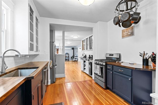 4321 Winona Ct, Denver, CO 80212 - kitchen with appliances with stainless steel finishes, a sink, butcher block countertops, and blue cabinetry