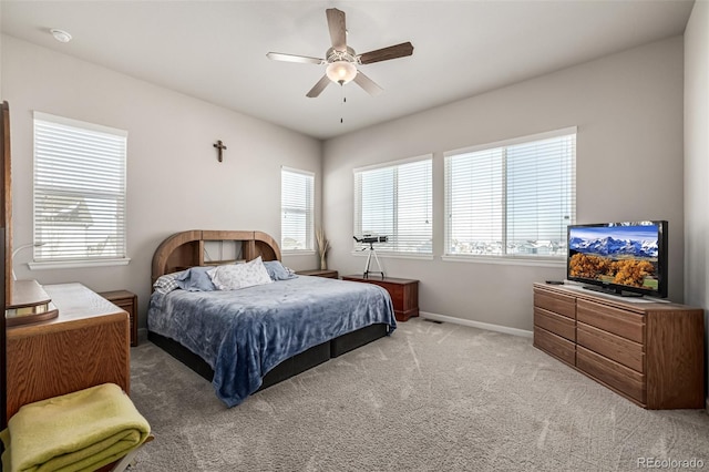 carpeted bedroom featuring multiple windows and ceiling fan