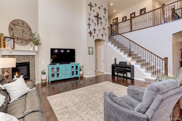 living area featuring baseboards, stairs, a towering ceiling, wood finished floors, and arched walkways