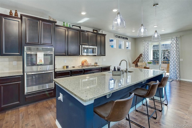 kitchen with a kitchen bar, dark wood-type flooring, backsplash, and stainless steel appliances