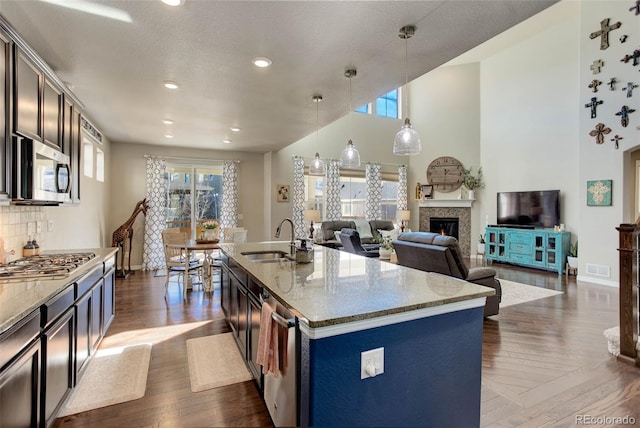 kitchen featuring dark wood finished floors, a glass covered fireplace, appliances with stainless steel finishes, and a sink