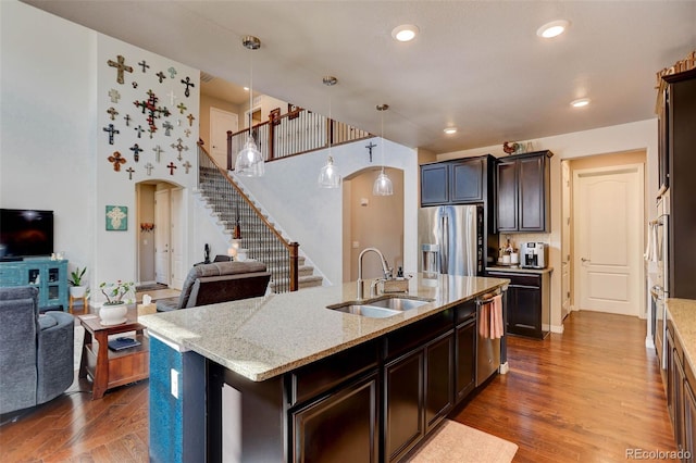 kitchen with dark wood finished floors, open floor plan, arched walkways, stainless steel appliances, and a sink